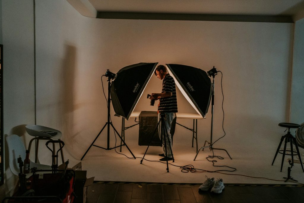 Photographer in a modern studio setting, surrounded by lighting gear and preparing for a photoshoot.