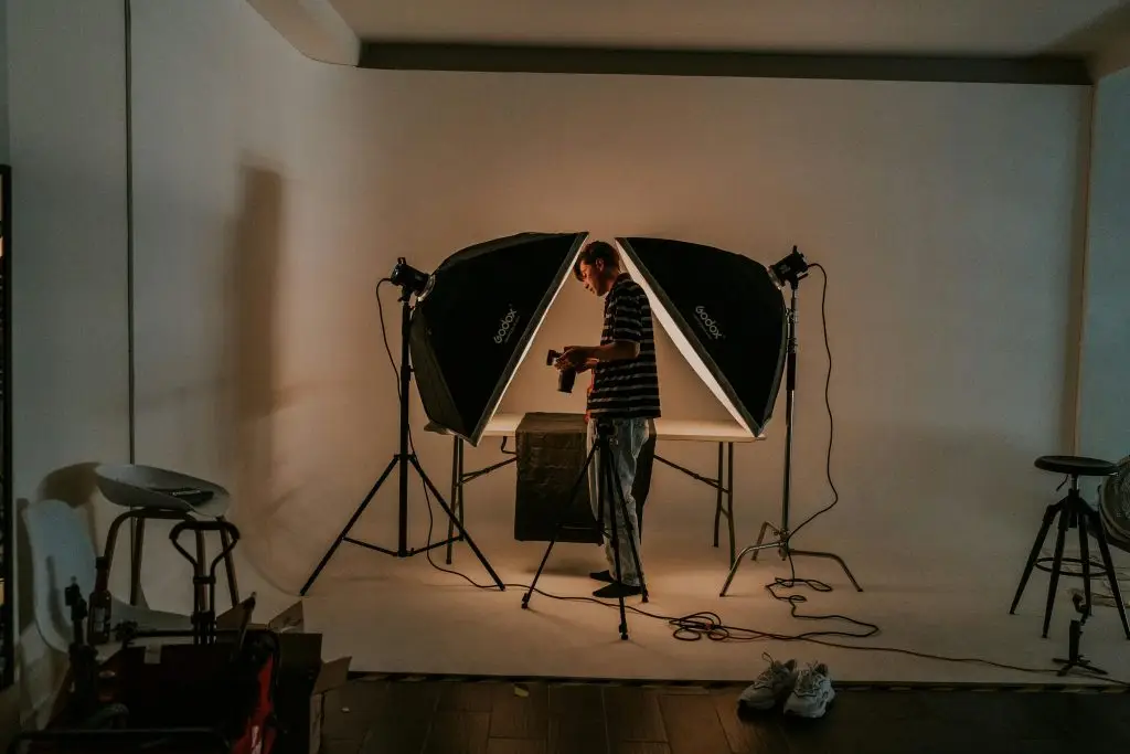 Uitrusting Photographer in a modern studio setting, surrounded by lighting gear and preparing for a photoshoot.